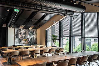 Photo of an interior of the Maisel brewery in Bayreuth. You can see a furnished meeting room with a picture of a person and a wolf.