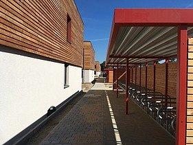 Foto des Studentenwohnheimes in Golm. Man sieht mehrere Holzgebäude und einen Fahrradüberstand.