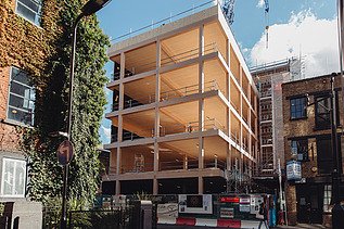 Foto des Rohbaus des mehrgeschossigen Bürogebäudes Black and White in London. Man sieht einen Gebäudekörper aus  Holz.