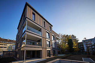 Photo of a multi-storey residential building with a wooden façade.