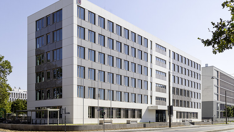 Foto eines großen, mehrgeschossigen, weißen Gebäudes.