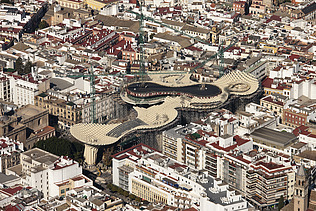 Photo of an aerial view of Seville. You can see the mushroom-like wooden construction of the Metropol Parasol Sevilla marketplace roof.