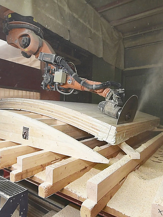 Foto eines Roboterabbundes. Der KUKA-Roboter sägt gerade eine LENO-Brettsperrholzplatte.