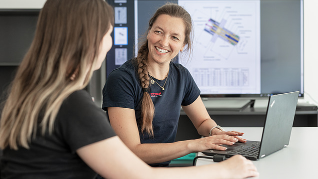 Photo of two women at a computer workstation.