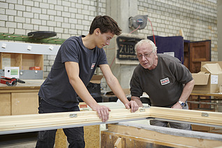 Sebastian works with an experienced carpenter.