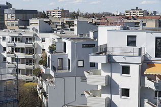 Foto eines mehrgeschossigen Gebäudes mit weißer Fassade. Aufstockung aus Holz.