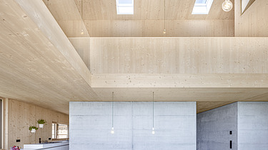 Photo of a modern wooden house with wooden facade. Dining room interior. Wooden and concrete walls.