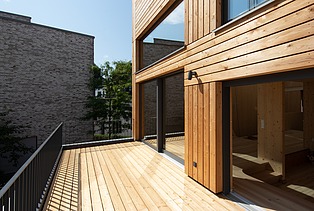 Foto eines Holzhauses. Detailbild der Holzterrasse im 1. Stock.