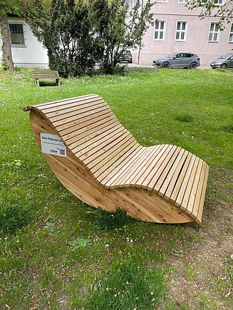 Foto einer Holzliege von ZÜBLIN Timber. Sie steht auf einer Wiese.