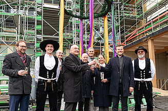 Aktuelles ZÜBLIN Timber. Projekt UmweltHaus Nürnberg. Alle freuen sich über ein gelungenes Richtfest. Foto von mehreren Personen unter einem Richtkranz. Projekt UmweltHaus Nürnberg.
