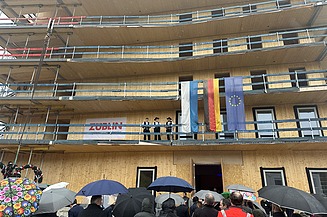 Foto beim Richtfest Grünes Zentrum Landshut. Zu sehen ist ein Holzbau im Rohbau mit Menschen davor.