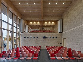 Foto eines Raumes mit roter Bestuhlung und vielen Holzoberflächen. JOWAT Haus der Technik.