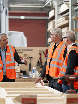 Drei Männer, die sich in der Fertigungshalle von ZÜBLIN Timber unterhalten.
