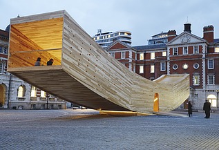 The Smile - Sculpture Design Festival London Photo of the curved wooden sculpture The Smile in London. The wooden box can be walked on and is intended to represent a smiling mouth.