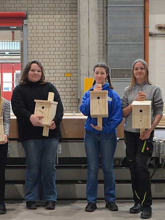 Foto von mehreren jungen Mädchen beim Girls Day in Aichach. Sie zeigen ihre gebauten Vogelhäuser aus Holz.