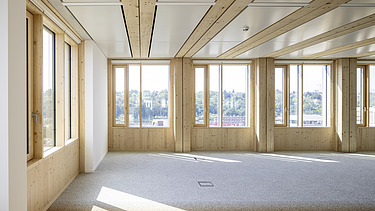 Interior photo of an empty office space. Glulam beams, wood-concrete composite ceiling.