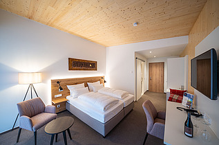 Foto eines Hotelzimmers im Weinhotel Gengenbach. Zu sehen ist ein möblierter Raum und eine LENO-Holzdecke.