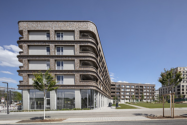 Foto eines auffälligen Holzgebäudes in L-Form mit Holzfassade.