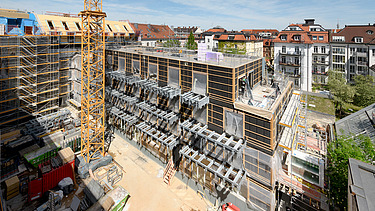 Foto des Rohbaus VINZENT in München. Zu sehen ist ein eingerüstetes, mehrgeschossiges Gebäude.