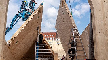 Photo of a timber construction site. Two carpenters are assembling LENO elements.