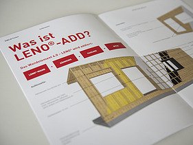 Foto der Innenseite der LENO-ADD-Broschüre von ZÜBLIN Timber. Man sieht einen Wandquerschnitt, der beschrieben wird und eine rote Überschrift.