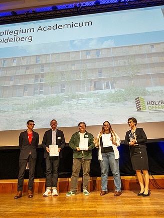 Photo of five people on stage at the award ceremony for the Baden-Württemberg Timber Construction Prize 2024.