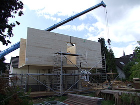 Foto eines Holzhauses mit Flachdach während der Montage. LENO-BSP.