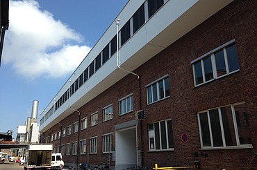 Aufstockung MAN Augsburg Foto eines mehrgeschossigen Gebäudes. Aufstockung aus Holz mit weißer Fassade und Flachdach.