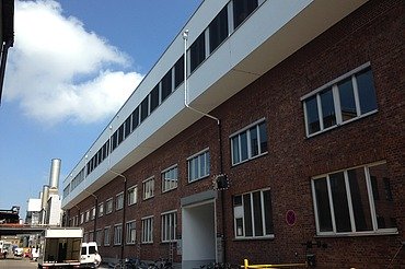 MAN Augsburg extension Photo of a multi-storey building. Wooden extension with white façade and flat roof.