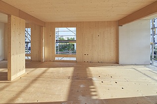 Innenaufnahme eines Gebäuderaumes aus Holz im Rohbaustand. Man sieht viele Holzoberflächen.