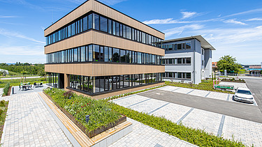 Foto eines Holzgebäudes mit Holz-Glasfassade und Flachdach.