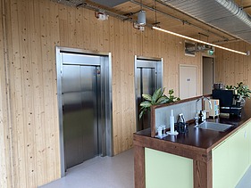 Photo of an interior of the Black and White office in London. You can see wooden surfaces and a kitchenette.