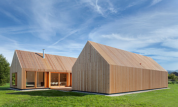 Foto eines modernen Holzhauses in U-Form mit Holzfassade. LENO-BSP.