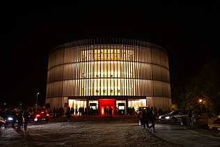Night shot of the Globe Theater in Coburg. You can see a round building made of wood.