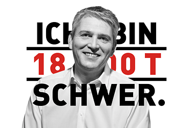 Foto von einem Mann in schwarz-weiß. Im Hintergrund ist eine rot-schwarze Schrift