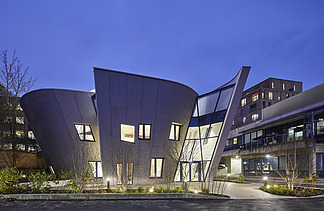 Photo of a building with a wooden façade and sloping walls. Shot at night.