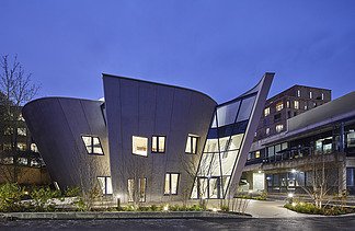 Photo of a building with a wooden façade and sloping walls. Shot at night.