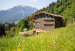Jägersberg Oberstdorf Photo of a wooden hotel in the middle of the mountain landscape.