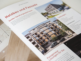 Foto der Innenseite der Image-Broschüre von ZÜBLIN Timber. Man sieht mehrere Gebäude aus Holz und die Überschrift Holzbau und Fassade.