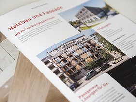Foto der Innenseite der Image-Broschüre von ZÜBLIN Timber. Man sieht mehrere Gebäude aus Holz und die Überschrift Holzbau und Fassade.