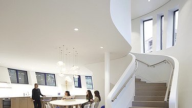 Photo of an interior with white walls and a large staircase.