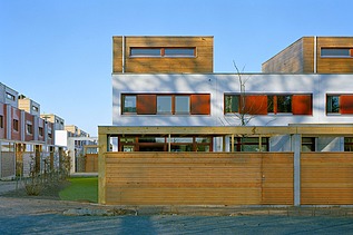 Photo of the terraced housing complex in Kranichstein. You can see several buildings made of wood.