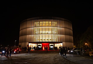 Nachtaufnahme des Globe Theaters in Coburg. Zu sehen ist ein rundes Gebäude aus Holz.