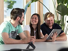 Foto von zwei Männern und einer Frau, die sich in einem Besprechungsraum unterhalten