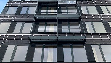 Foto eines mehrgeschossigen Gebäudes mit schwarzer Fassade.