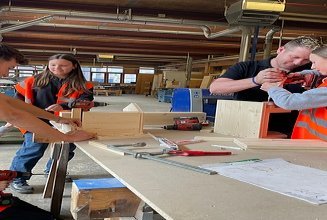 Photo of five people working with cordless screwdrivers and wood.