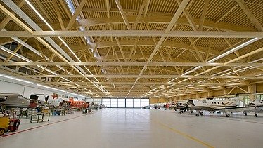 Photo of the Pilatus CH-Stans assembly hall. A large glulam roof construction can be seen.