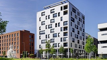 Foto eines mehrgeschossigen Gebäudes aus Holz mit weißer Fassade.