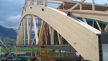 Photo of the Pilatus CH-Stans assembly hall. You can see a large, curved glulam beam