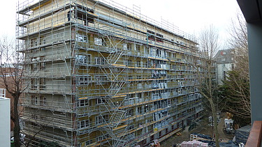 Photo of a multi-storey building in shell condition with a timber extension.